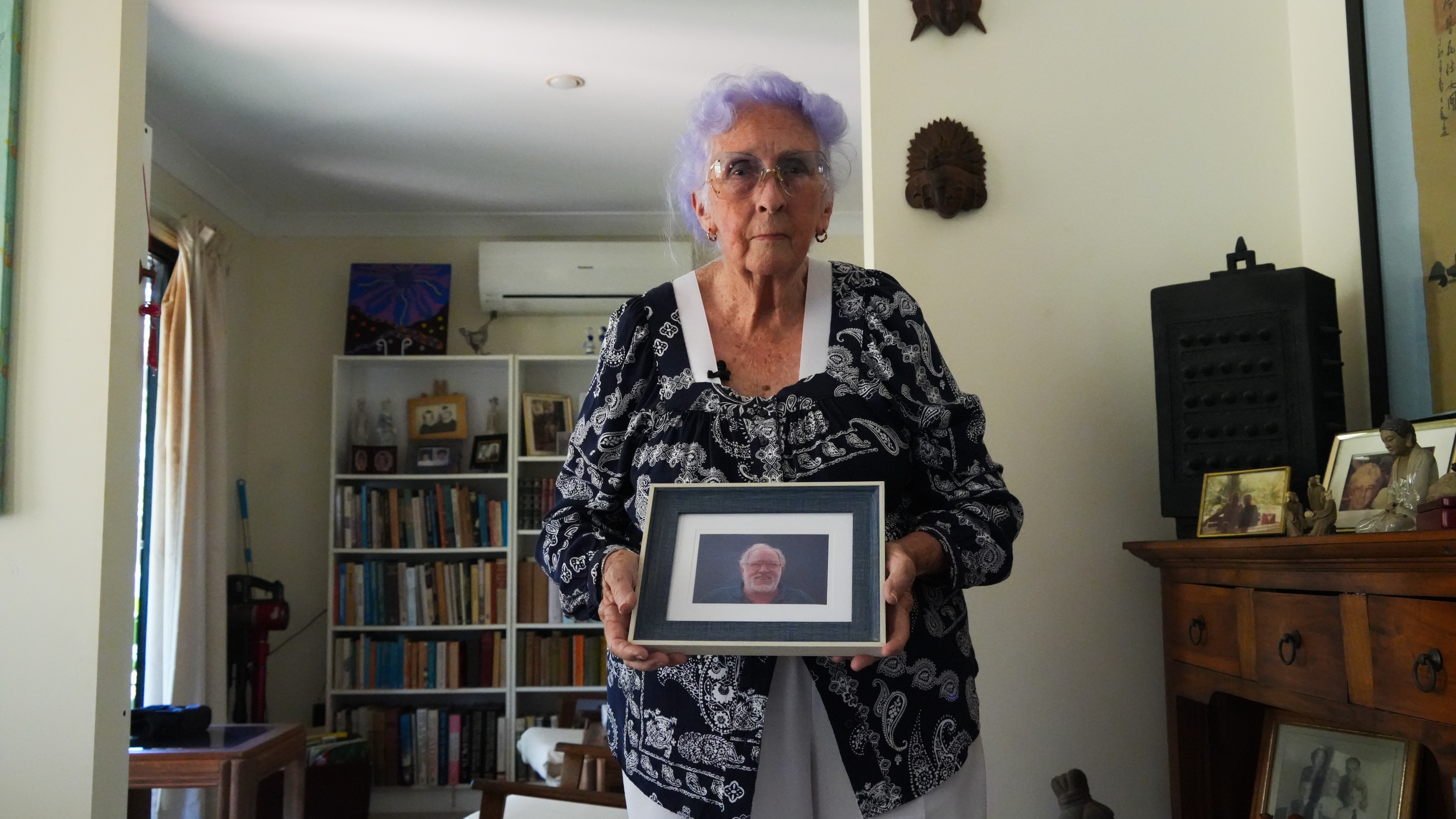 lady holding photoframe of elderly man