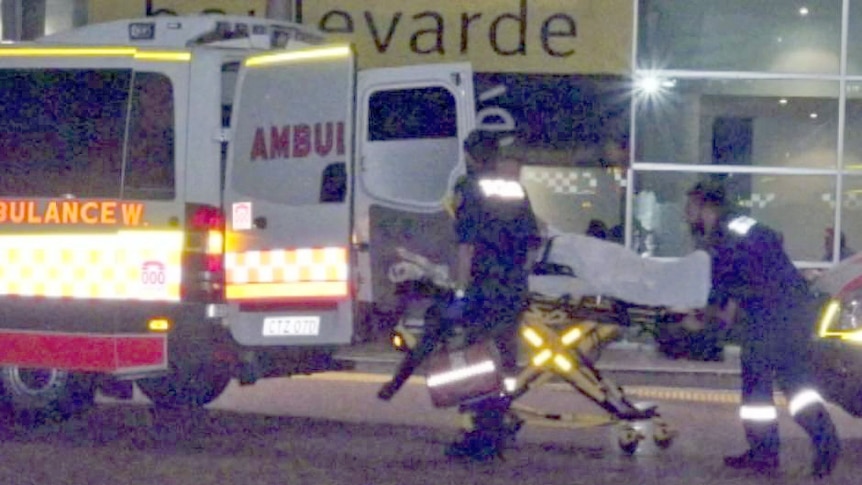 Person being loaded into ambulance by two paramedics during dance party.