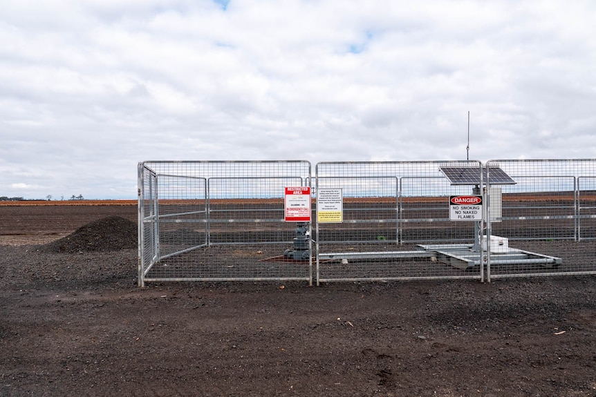 A water monitoring bore with a cage around it on a farm.