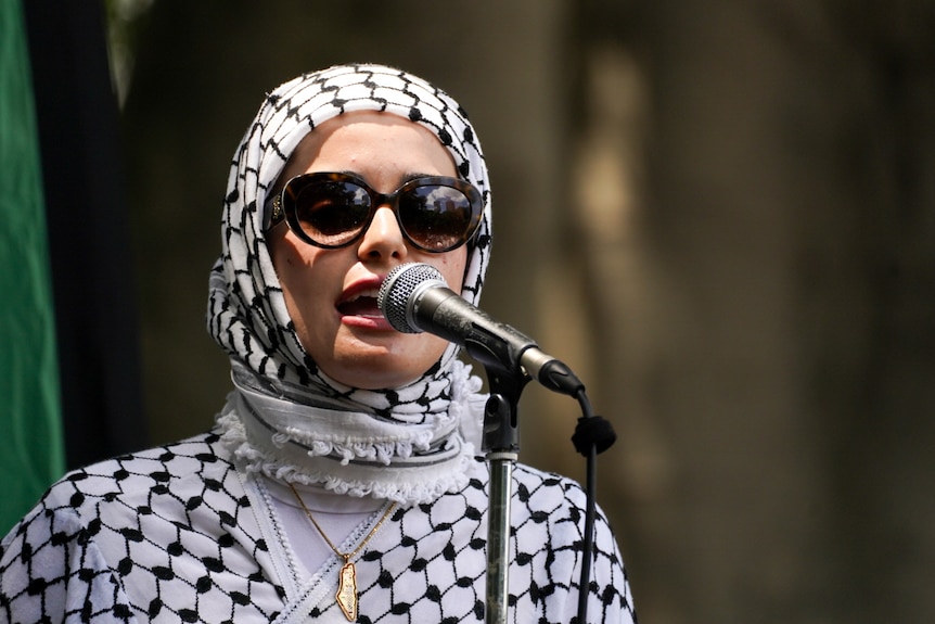 Woman in sunglasses speaks into a microphone