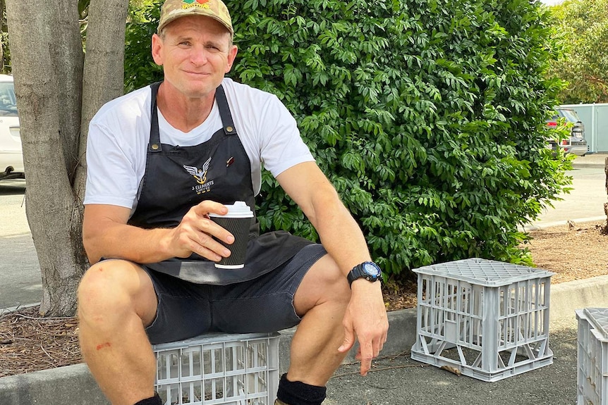 Tim Thomas holds a takeaway coffee from his shop while sitting on a milk crate.