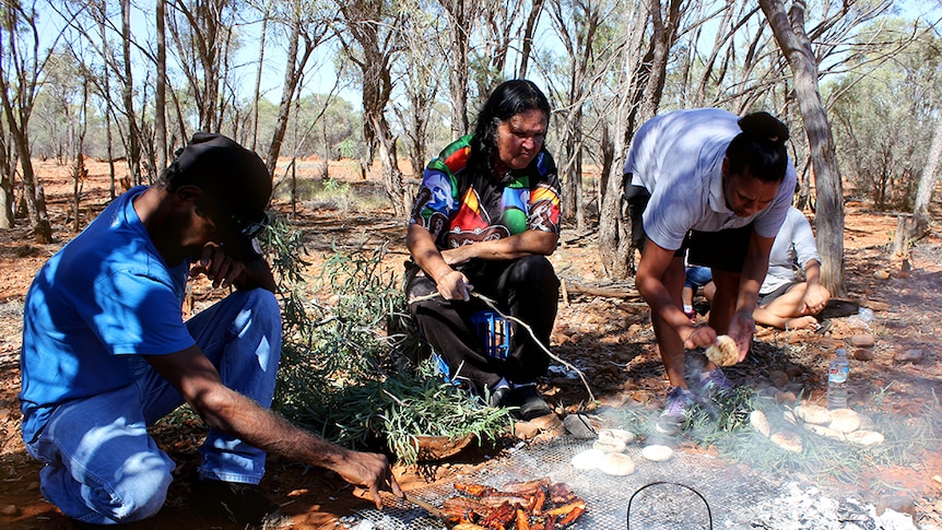 Aboriginal people cooking some bush tucker.