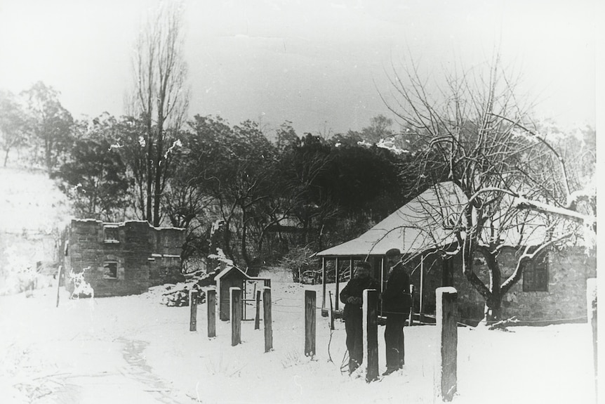 black and white photo of two men standing in snow