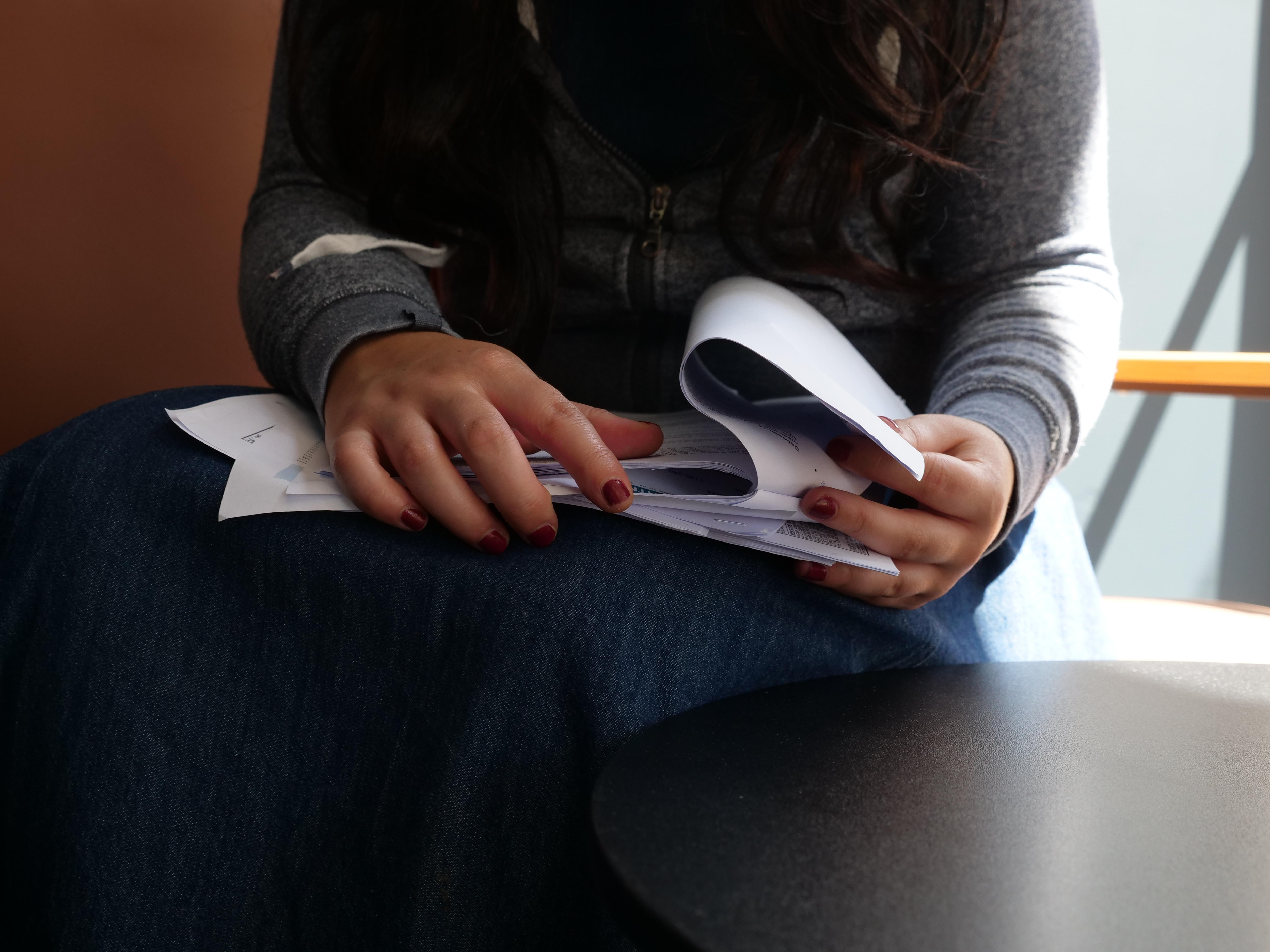 Um close da mão de uma mulher embaralhando papéis. 