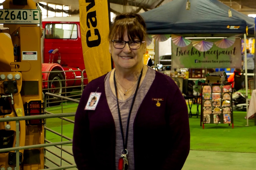 A woman with a fringe and glasses inside wearing a lanyard and cardigan 