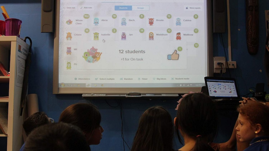 a smartboard with icons on it and a warning sign and children looking on