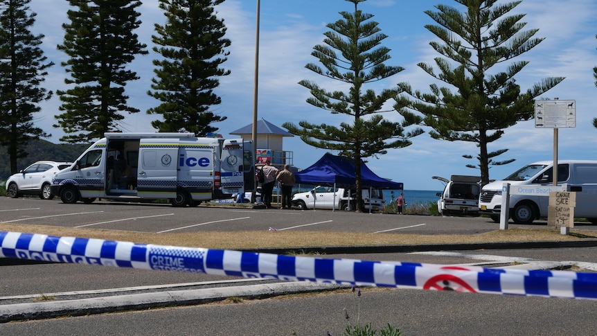 A police van and blue gazebo behind a car park and police tape.