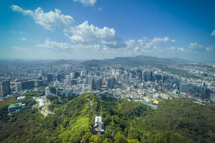 A view of Seoul from above - the densely built skyscrapers are surrounded by green hills