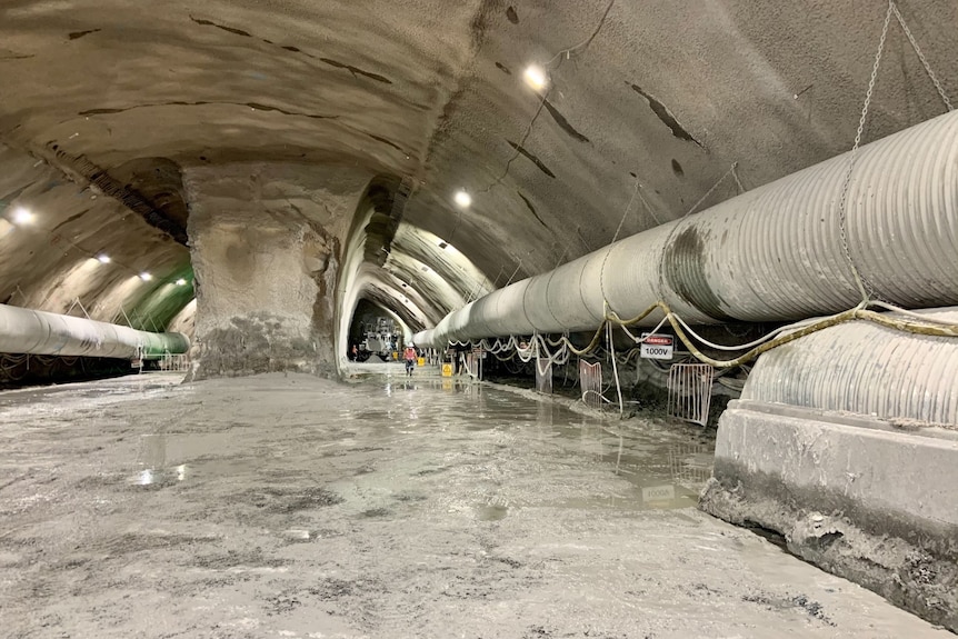 A large underground tunnel with a person in high visibility gear at the end