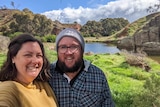 a man and woman smile in front of a lake. 