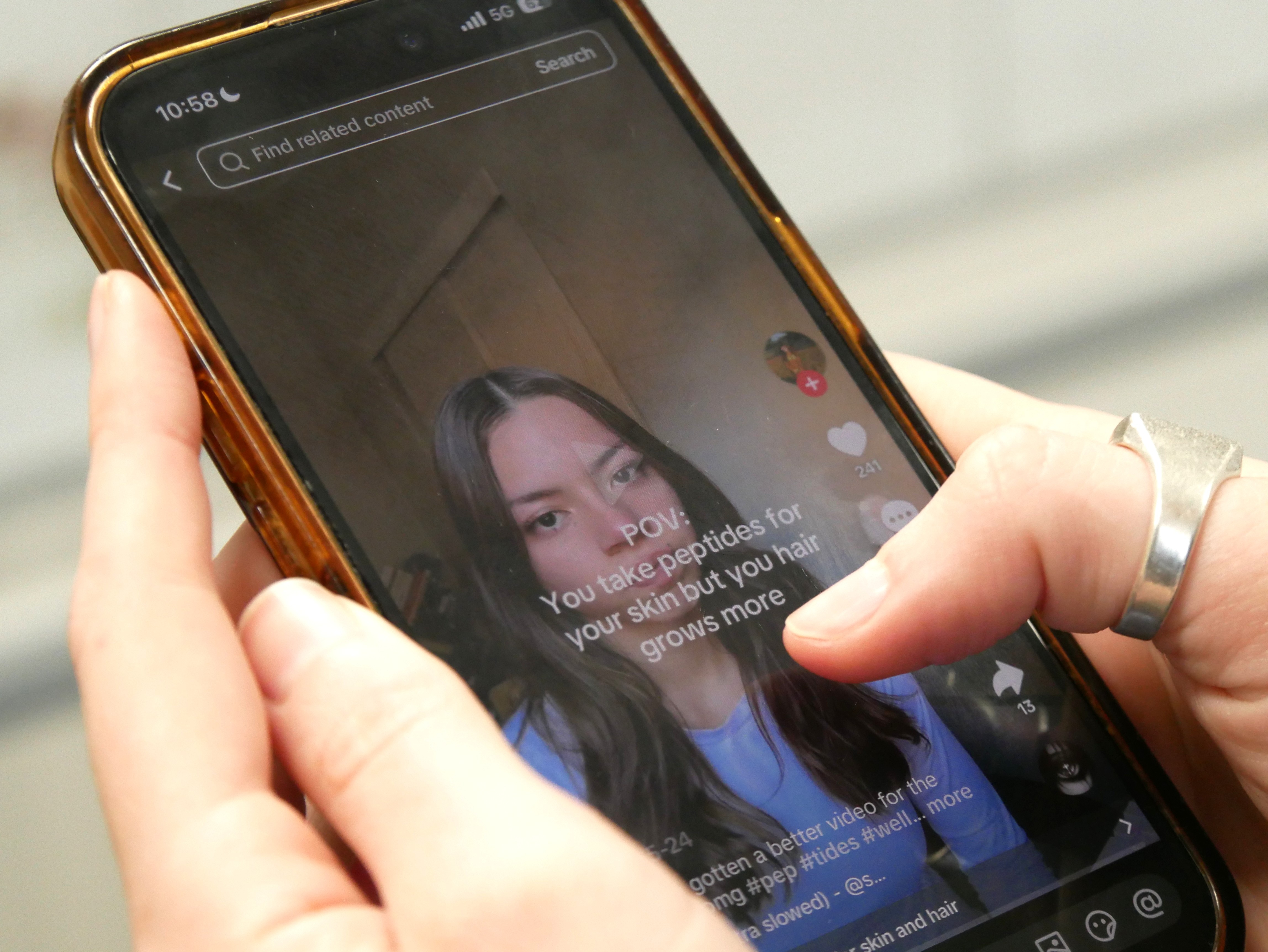 Fingers hovering over a phone showing a video about peptides.