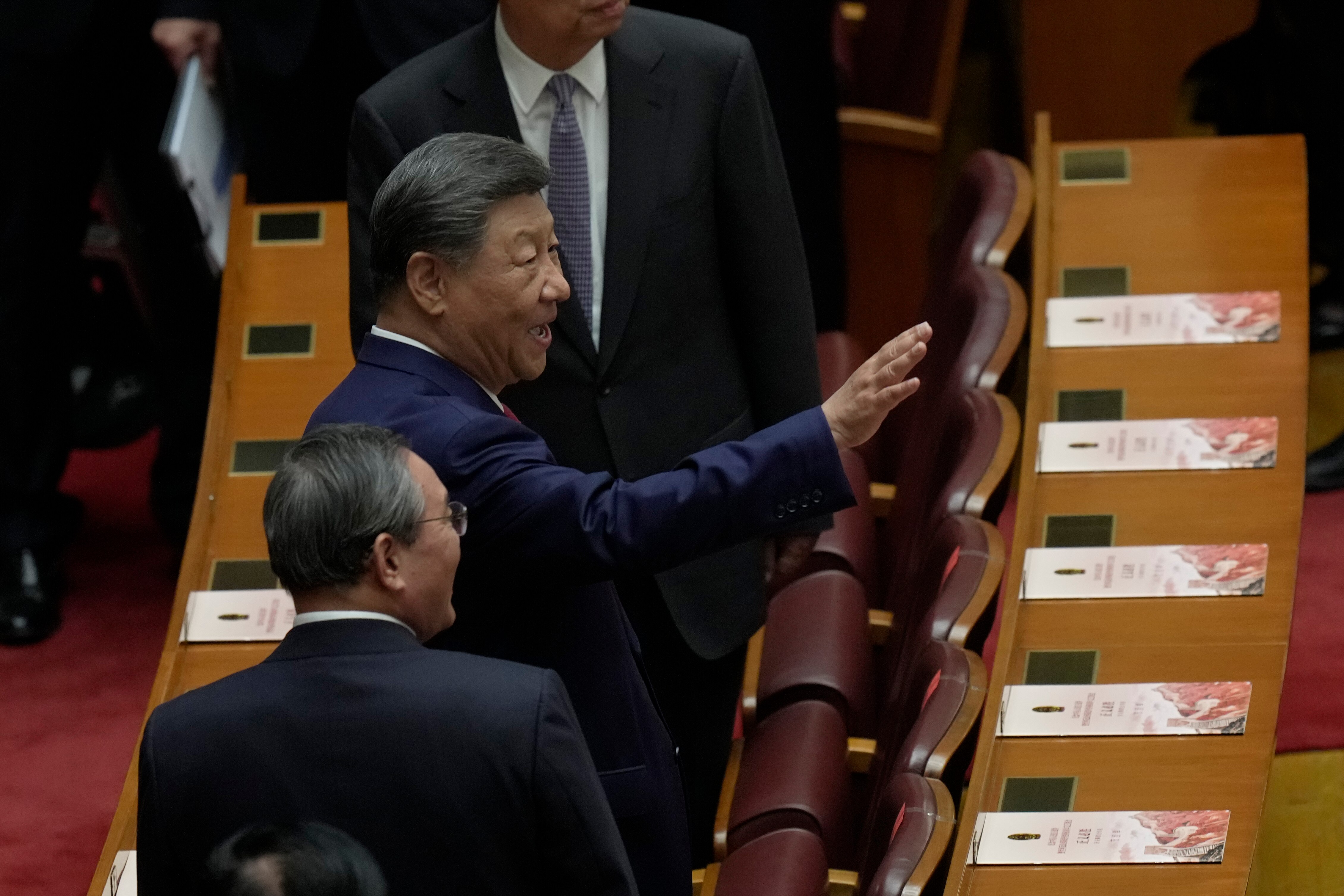 China's President Xi Jinping raises a hand as if waving to someone.