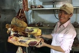Fiona McBean holds some beef hanging from hooks in the farm cool room.