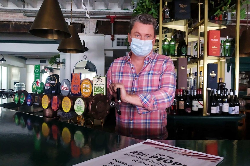 Jason Hirt stands at the bar with a mask on.