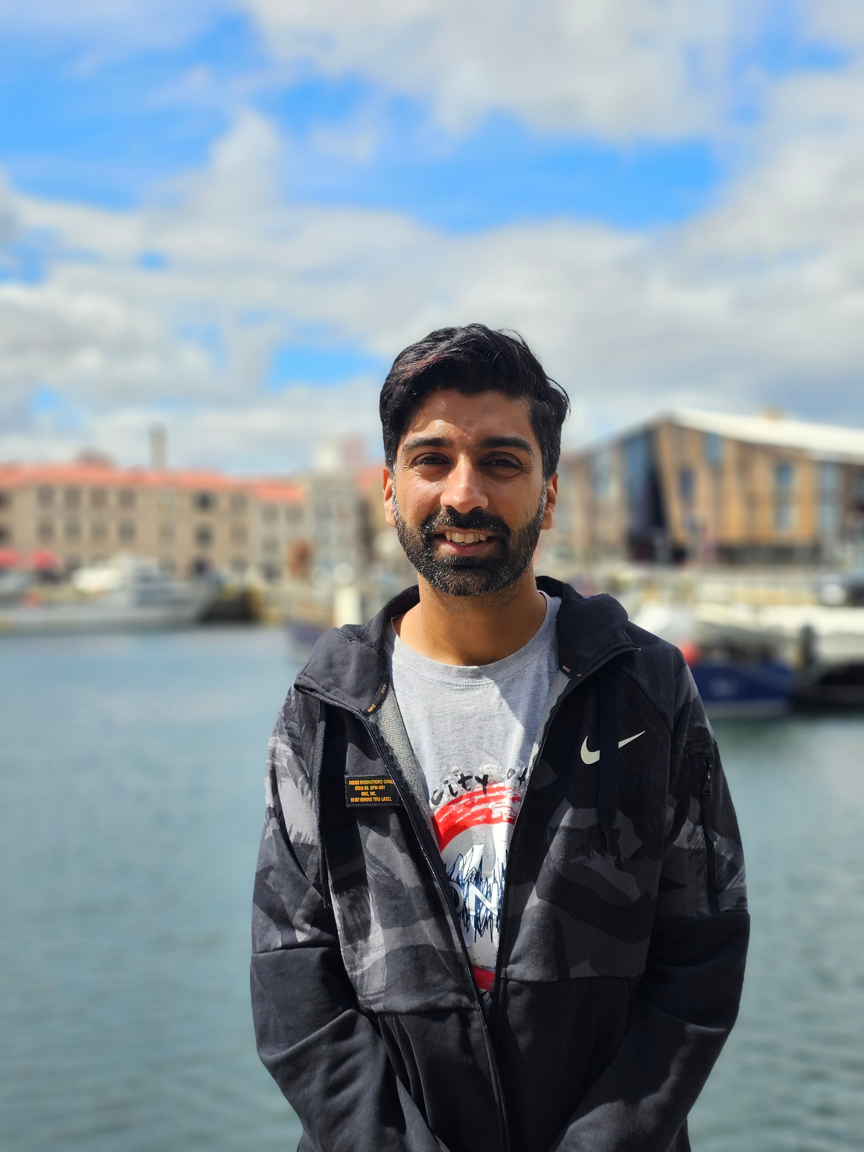 A man smiling to camera with building in the background