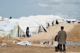 Two boys hold a water container looking over the camp.