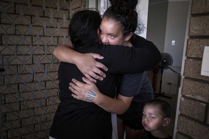 Two women embrace at a front door.