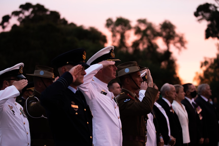 A row of men salute during an Anzac service