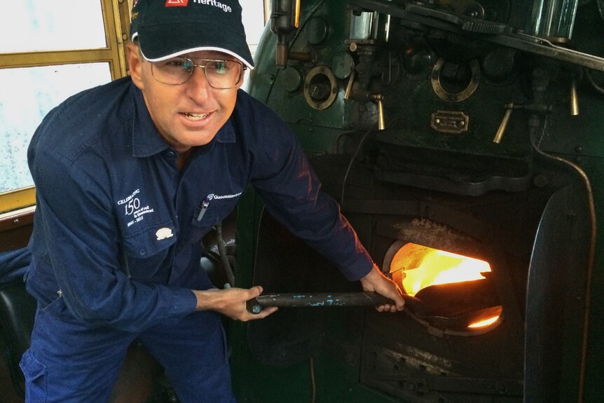 A Queensland Rail staff member shovels coal into a train engine in Brisbane.