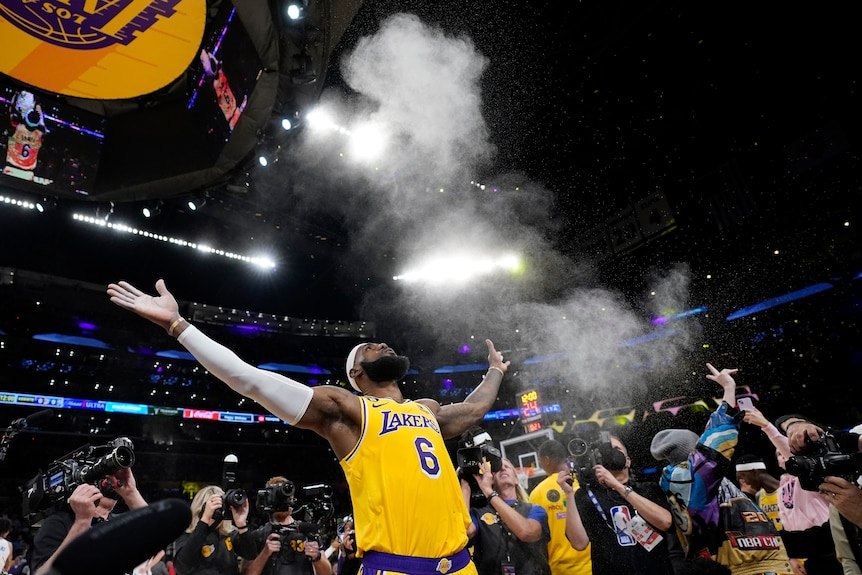 Basdketballer LeBron James looks up to the ceiling of a stadium as he throws powder in the air before a big NBA game. 