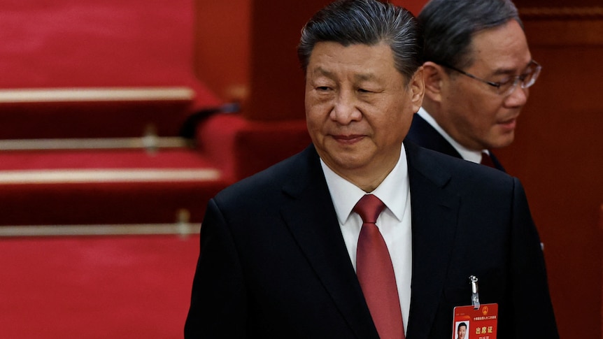 Chinese President Xi Jinping and Premier Li Qiang dressed in suits stand inside a room.