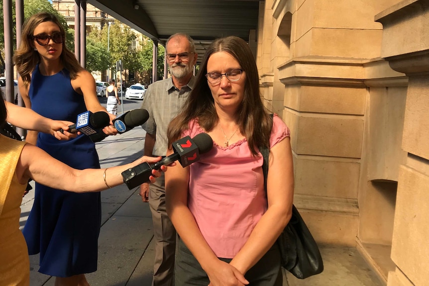 A woman outside an Adelaide court surrounded by media.
