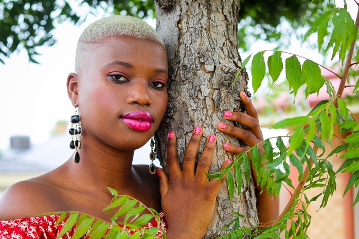 Portrait of an African woman standing under a tree.