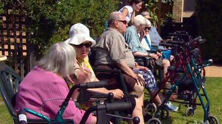 Elderly people enjoy the sunshine in the gardens of their retirement home.