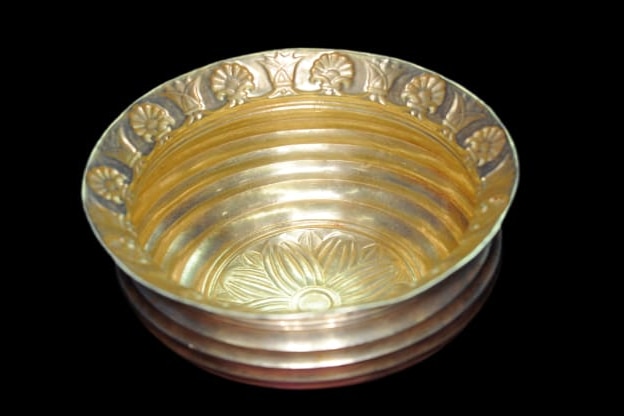 A gold bowl with a scalloped design around the rim.