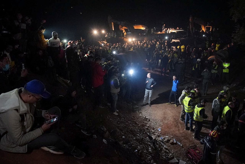 Dozens of people gather around the site as rescuers use machinery to dig to the trapped boy, February 4, 2022.