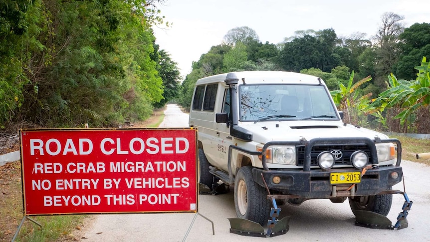A red road closure sign next to a modified 4WD on an empty road