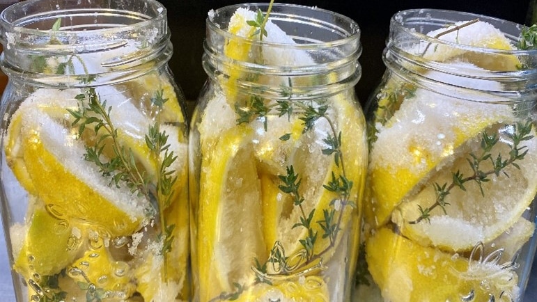 Three open jars filled with lemon wedges, salt and thyme sprigs.
