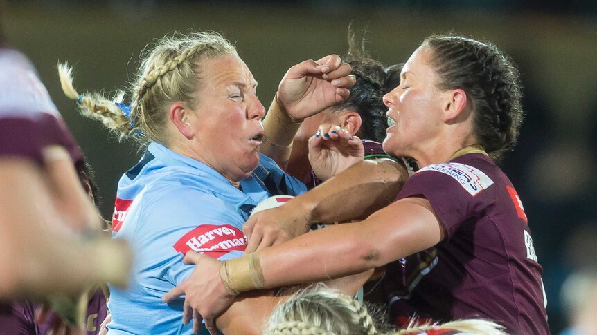 Rebecca Young of the blues is tackled by a number of maroons players