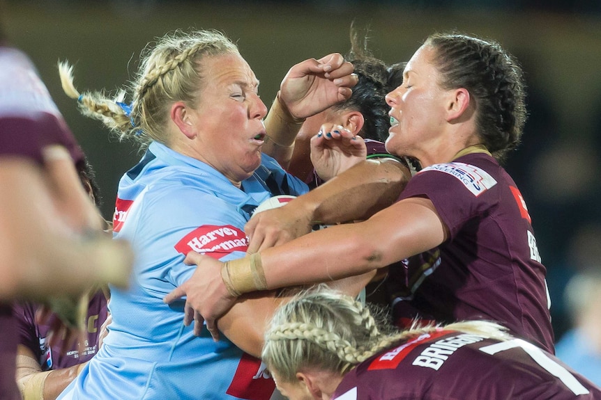 Rebecca Young of the blues is tackled by a number of maroons players