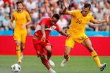 A Peruvian footballer tries to keep his balance near the ball as an Australian defender closes in at the World Cup.
