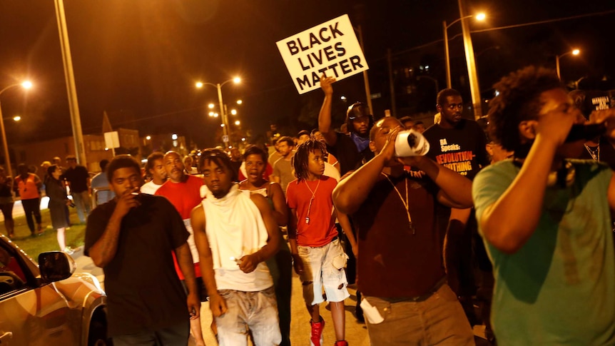 Protestors hold a 'Black Lives Matter' sign during a night march following the police shooting of a man in Milwaukee.