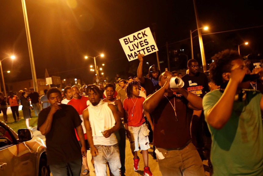Protestors hold a 'Black Lives Matter' sign during a night march following the police shooting of a man in Milwaukee.