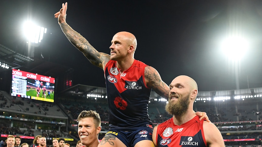 AFL player sitting on teammates shoulders after winning a match