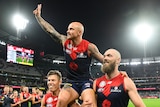 AFL player sitting on teammates shoulders after winning a match