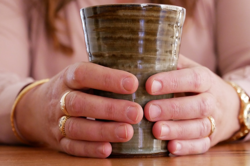 a woman's hands holding a coffee mug 
