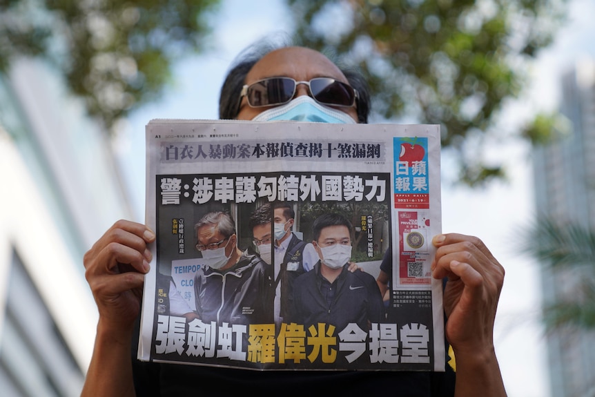 一名戴墨镜男子手中举着报纸。