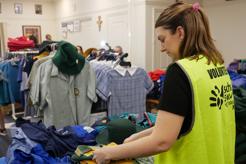 A woman in a green high vis vest folds a shirt