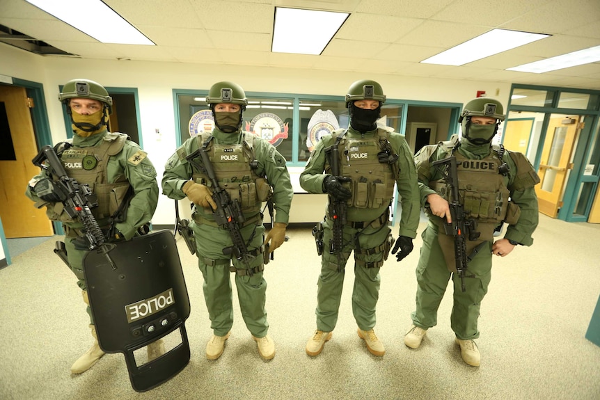 Four SWAT team members are seen dressed in their uniforms and armed.
