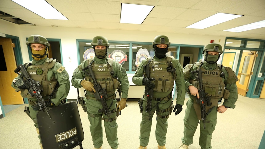 Four SWAT team members are seen dressed in their uniforms and armed.