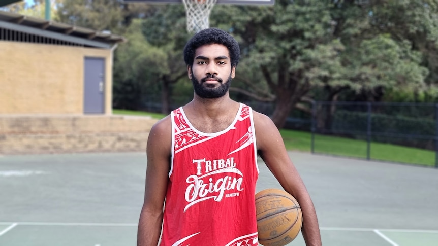 Buru standing on a basketball court with a basketball on his hip