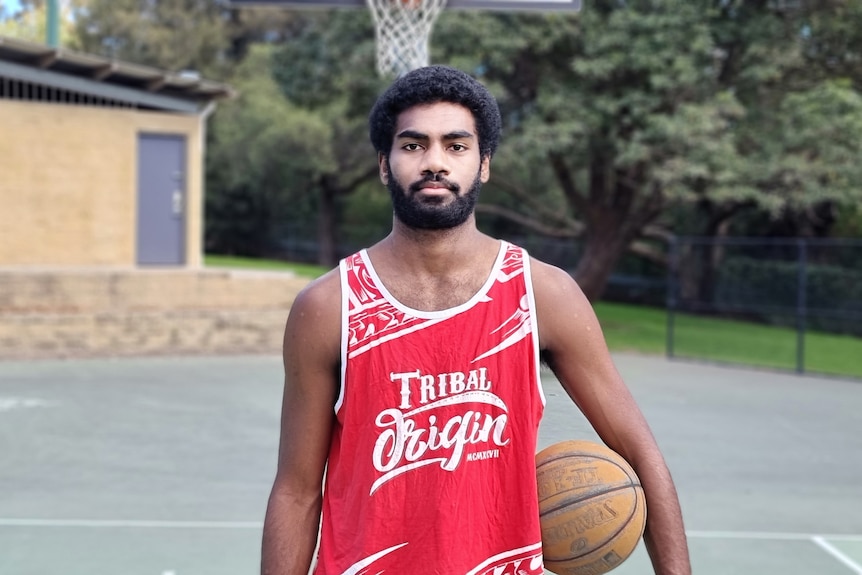 Buru standing on a basketball court with a basketball on his hip