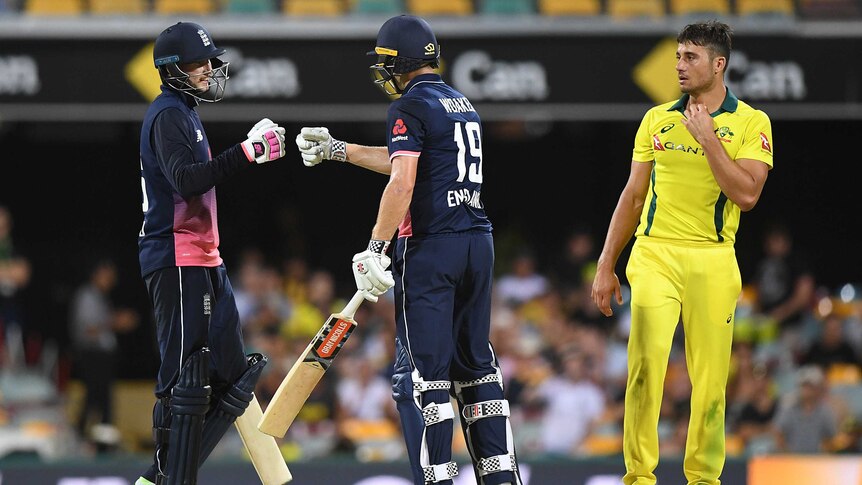 Joe Root and Chris Woakes celebrate with a fist bump as Australia's Marcus Stonis looks on from the right