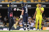 Joe Root and Chris Woakes celebrate with a fist bump as Australia's Marcus Stonis looks on from the right