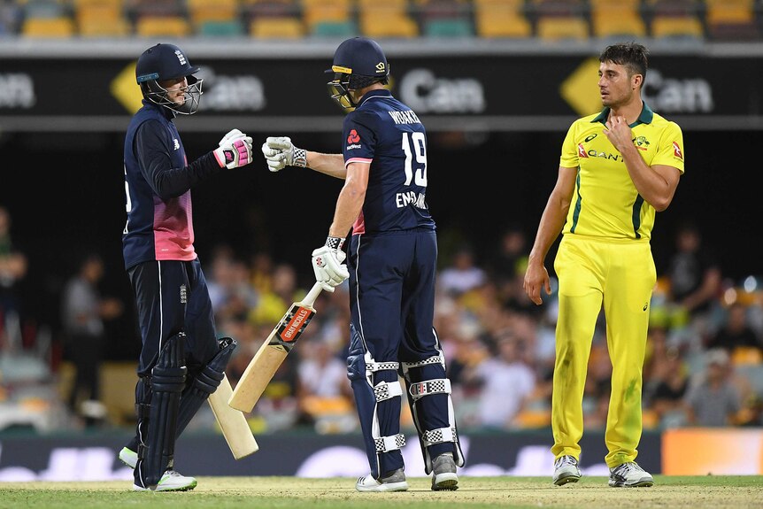 Joe Root and Chris Woakes celebrate with a fist bump as Australia's Marcus Stonis looks on from the right