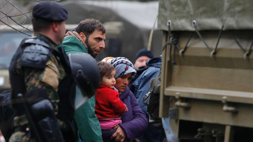 Macedonian soldiers escort asylum seekers who have crossed the border into army trucks.